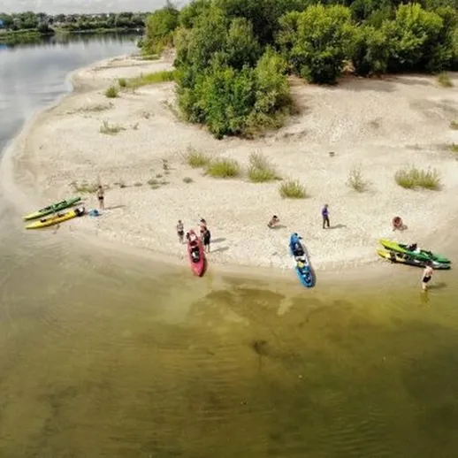 Групповой отдых на песчаном берегу реки с каяками и каноэ в солнечный день