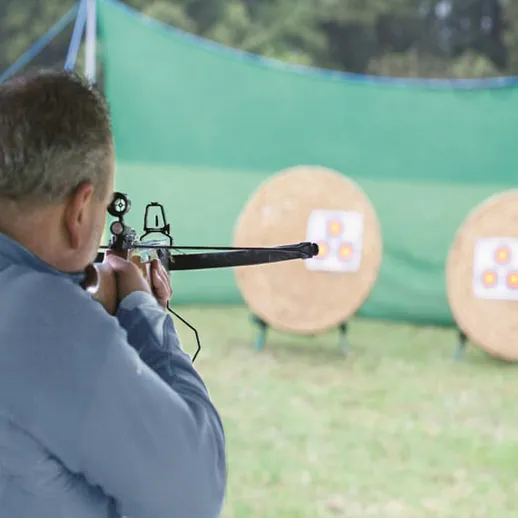 Стрелок прицеливается в мишени на соревнованиях по стрельбе в ясный день на открытом воздухе