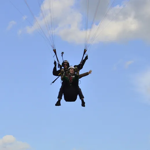 Люди с парашютами в небесах во время прыжка над живописным пейзажем в ясный солнечный день