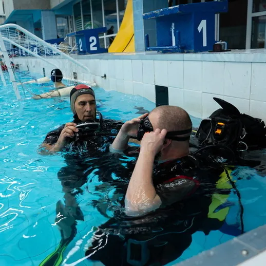 Дайверы готовятся к тренировке в бассейне в спортивном комплексе в течение дня