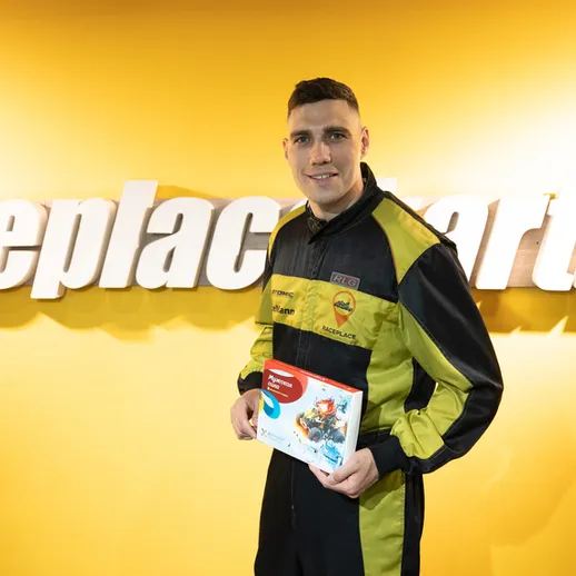 Молодой гонщик с наградой на фоне стенда автоспорта в спортивной одежде