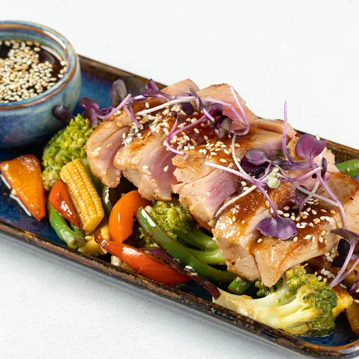 Качественное блюдо с куриным мясом и овощами, приготавленное на гриле, поданное в ресторане в вечернее время