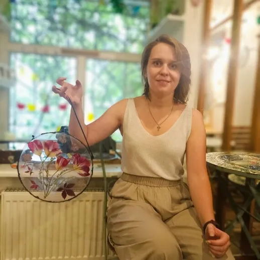 Женщина с декоративным кругом в руках, сидящая в уютном пространстве с видом на зелень