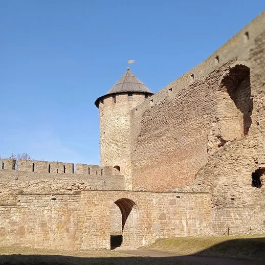Средневековая крепость с круглой башней в ясный день, расположенная на фоне голубого неба