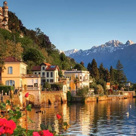 Живописный вид на озеро с цветущими розами и горной цепью на фоне в солнечный день