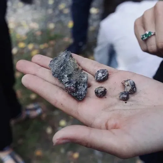 Найденные минералы и камни на прогулке в лесу осенью, человек держит находки в руке