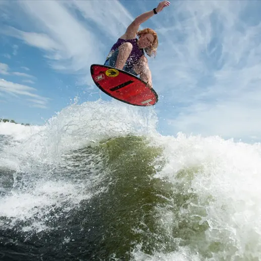 Серфингист выполняет трюк на волне в солнечный день на озере, наслаждаясь активным отдыхом и свободой