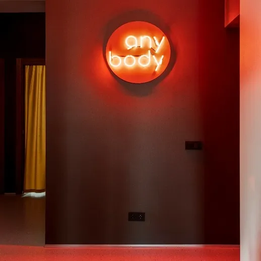 Яркая неоновая вывеска any body в современном интерьере помещения с теплым освещением