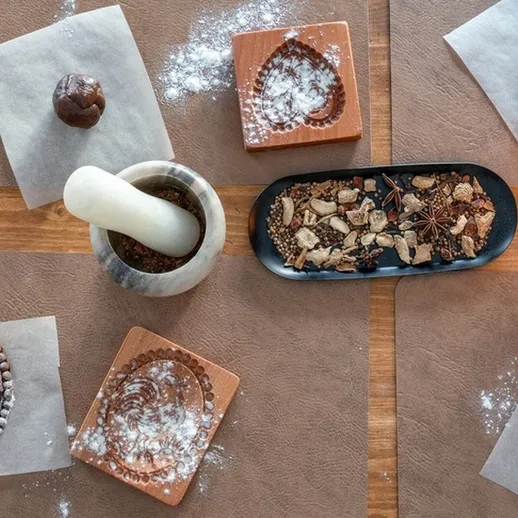 Процесс приготовления домашнего печенья с использованием деревянных форм для выпечки на кухонном столе