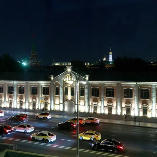 Ночной пейзаж московской улицы с автомобилями и историческим зданием в освещении