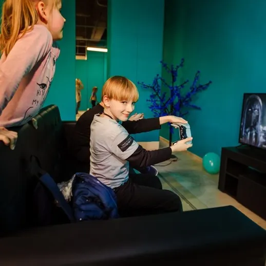 Дети играют в видеоигру в игровой комнате с яркими стенами и телевизором