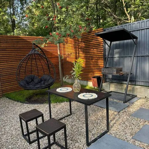 Уютная зона отдыха с садовой мебелью и зелеными растениями в летний день