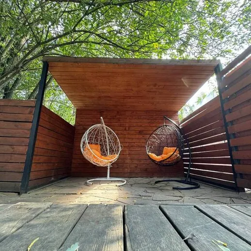 Уютный уголок для отдыха с висячими креслами в зеленом саду на солнечном дне