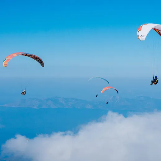 Парапланеристы летают над облаками в ясный день над горами