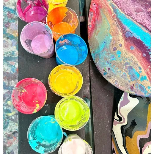 Яркие краски для творчества на столе с абстрактными рисунками в мастерской