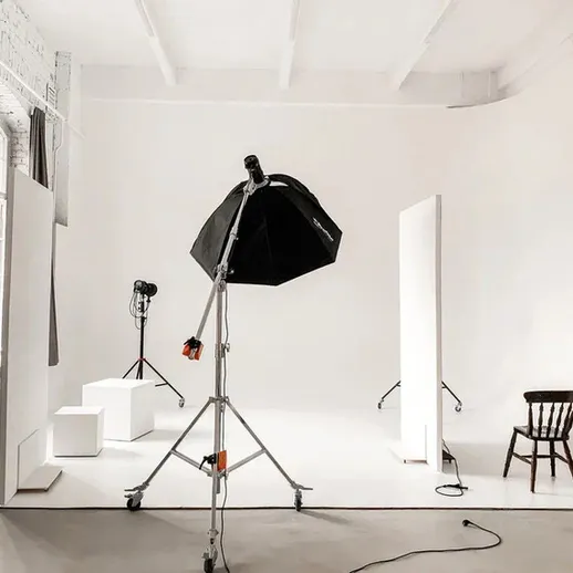 Студийная фотосъемка в пустом помещении с осветительным оборудованием и стульями