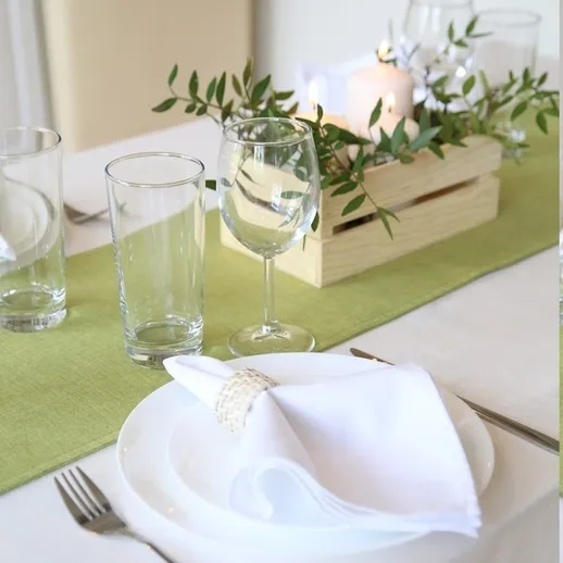 Элегантная столовая сервировка с зелеными акцентами и элементами декора в светлом интерьере