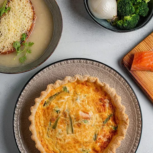 Вкусный овощной пирог с брокколи и копченым лососем на стильном столе в уютной обстановке