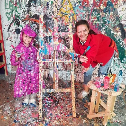 Семейное творчество: ребенок и взрослый расписывают холст в красочном арт-пространстве