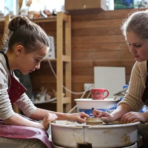 Девочка и женщина создают глиняные изделия на гончарном круге в мастерской в осенний день