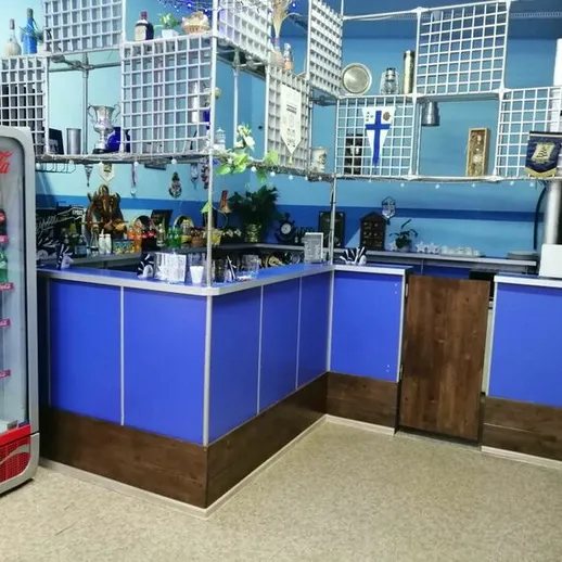 Интерьер яркого бара с синими стенами и деревянной мебелью, расположенного в уютном районе города