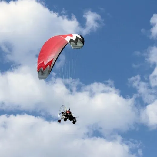 Параплан на фоне голубого неба с облаками, пилотирует воздушный транспорт в ясный день