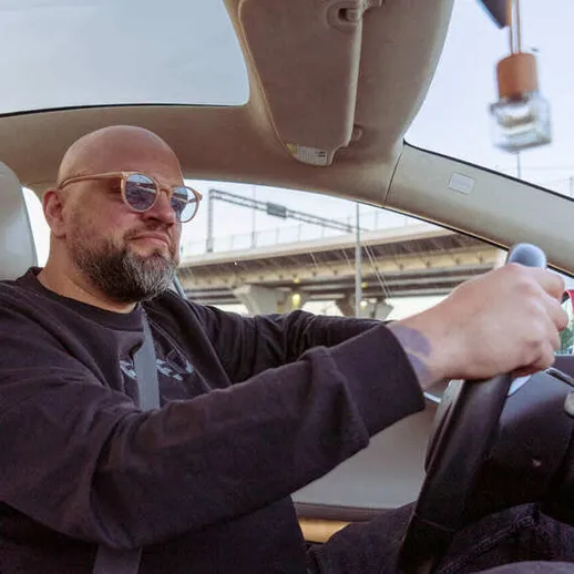 Мужчина за рулем автомобиля на фоне мостов в светлый день