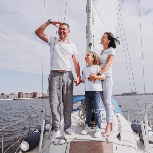 Семья наслаждается днем на парусной яхте в городе у воды под ясным небом