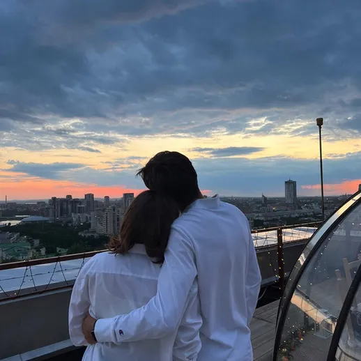 Вечерний закат на крыше города: пара наслаждается моментом у океана