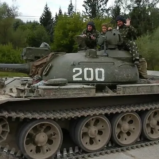 Танковая боевая машина на учениях в лесу с военнослужащими на борту, возможно, весной или летом