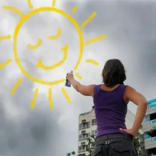 Женщина расписывает серое небо ярким солнцем с улыбкой в городе во время облачного дня