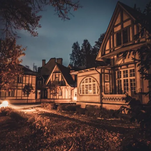 Уютный загородный дом с красивой архитектурой в вечернее время на фоне темного неба