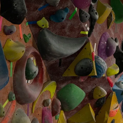 Тренировочная стенка для скалолазания с разноцветными зацепами в спортивном зале