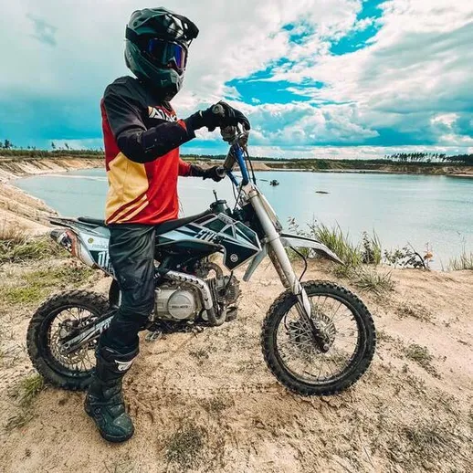 Мотоциклист на внедорожном мотоцикле у озера в ясный день