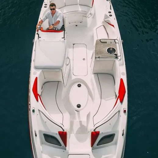 Мужчина управляет небольшой моторной лодкой на спокойной воде в солнечный день