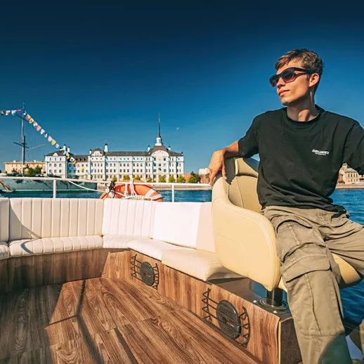 Молодой человек на лодке в солнечный день у набережной города