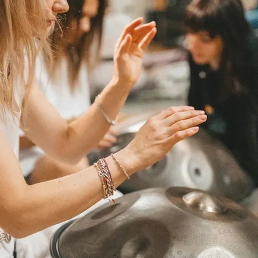 Три музыканта учатся играть на хэндпан в уютной студии в вечернее время