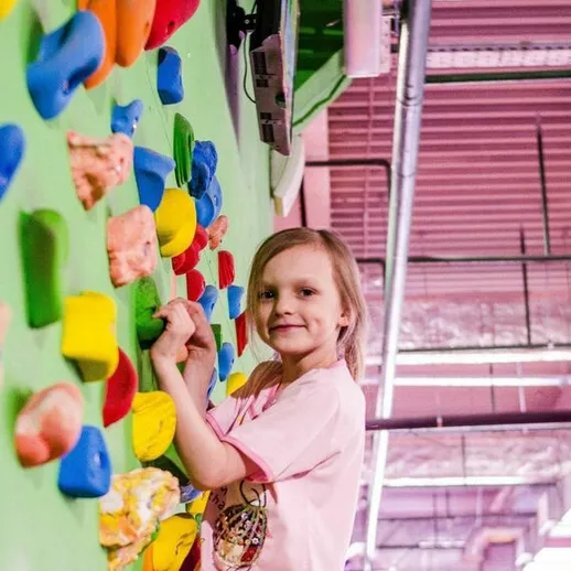 Малышка преодолевает стены скалодрома в спортивном центре, занимаюсь скалолазанием в солнечный день