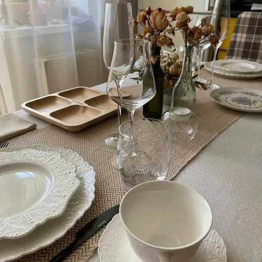 Элегантно сервированный стол с белой посудой и цветами в вазах в солнечной комнате в уютной квартире