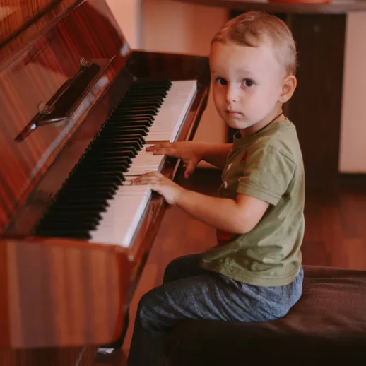 Мальчик играет на пианино в уютной комнате в начале вечера