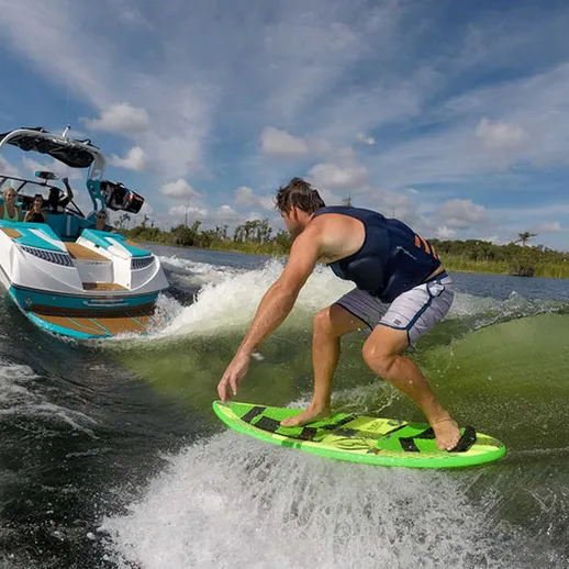 Завораживающий серфинг на волнах рядом с катером в солнечный день на водоеме