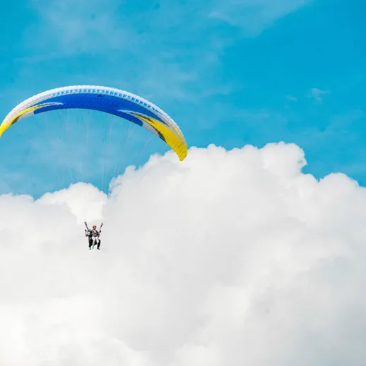 Парапланерист парит над облаками в ясный день с голубым небом