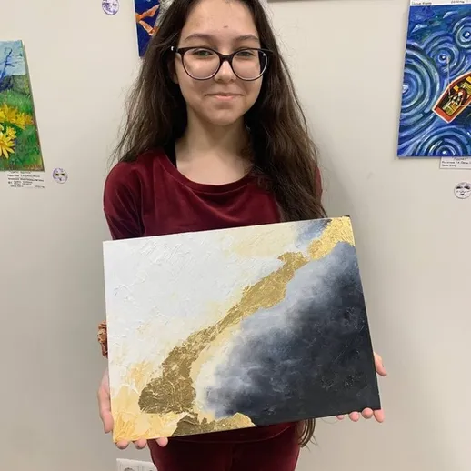 Участница выставки искусств демонстрирует свою картину в художественной галерее