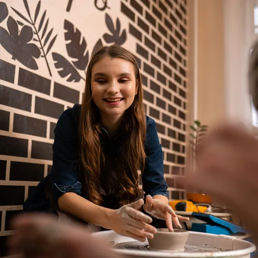 Молодая девушка занимается гончарным мастерством в студии с современным интерьером