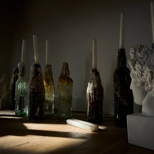 Скульптурные головки и бутылки с восковыми свечами в мягком свете комнаты
