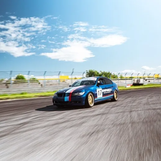 Спортивный автомобиль на гоночной трассе под ярким небом в разгар дня, демонстрирующий высокую скорость и маневренность
