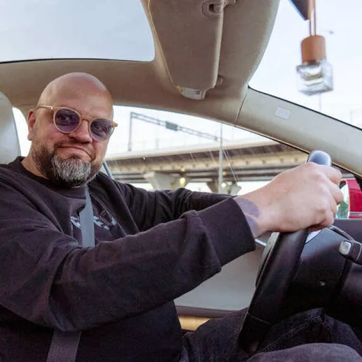 Мужчина едет в автомобиле по мосту в солнечный день, наслаждаясь поездкой на свежем воздухе