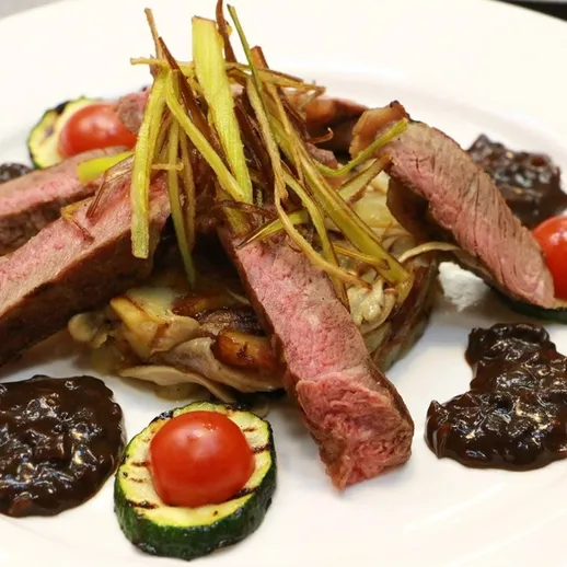 Вкусный стейк с гарниром и соусом подано на белой тарелке в ресторане