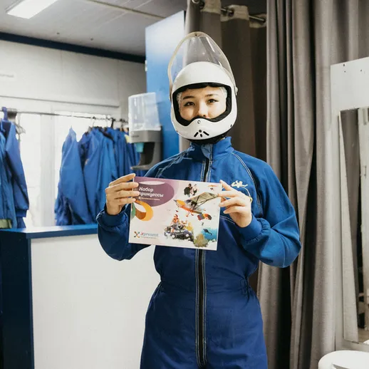 Участник космического проекта держит буклет в специализированном костюме в подготовительном центре