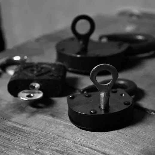 Три разных замка на деревянной поверхности, символизирующие безопасность и защиту, сфотографированы в тусклом освещении